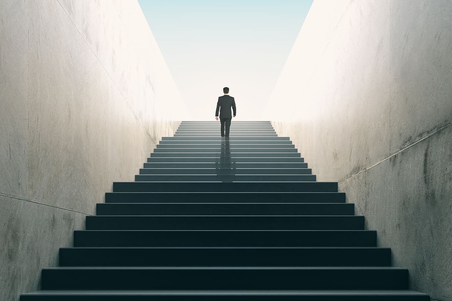 A person walking up some stairs with the light coming from above