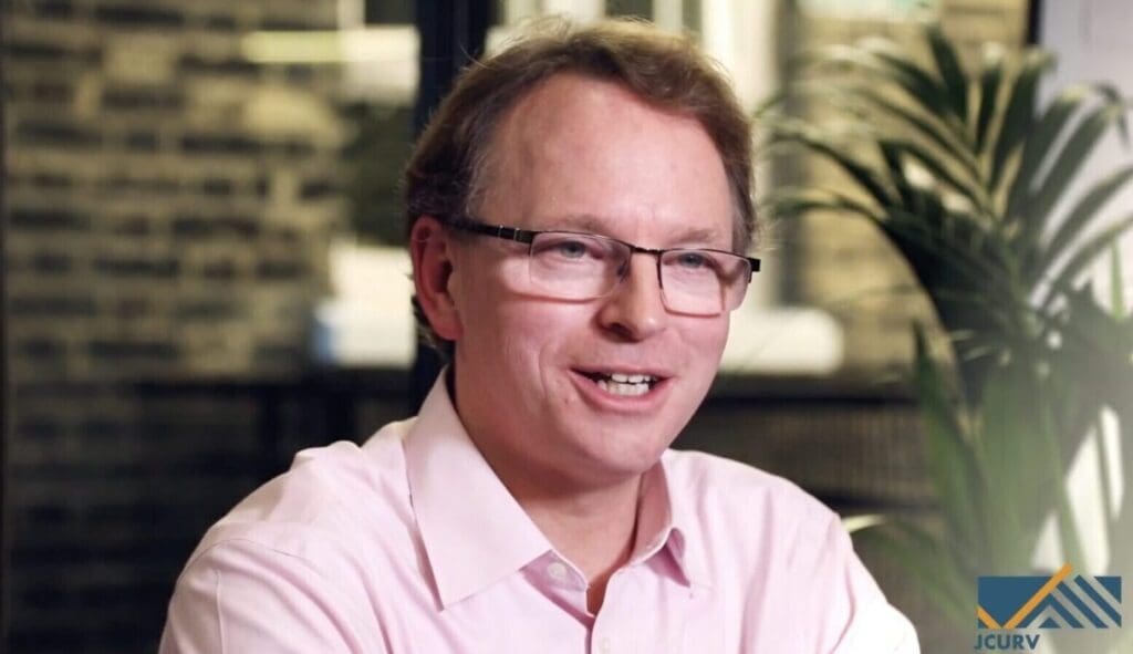 A man with glasses and a pink shirt