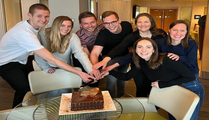 A group of people cutting a cake on top of a table.